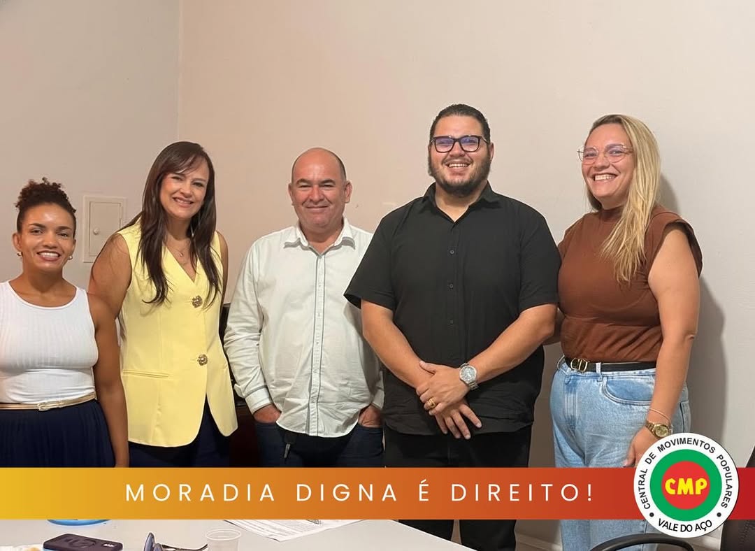 Cinco participantes posam para foto durante reunião em Caratinga, com faixa “Moradia digna é direito!” e logomarca da CMP Vale do Aço