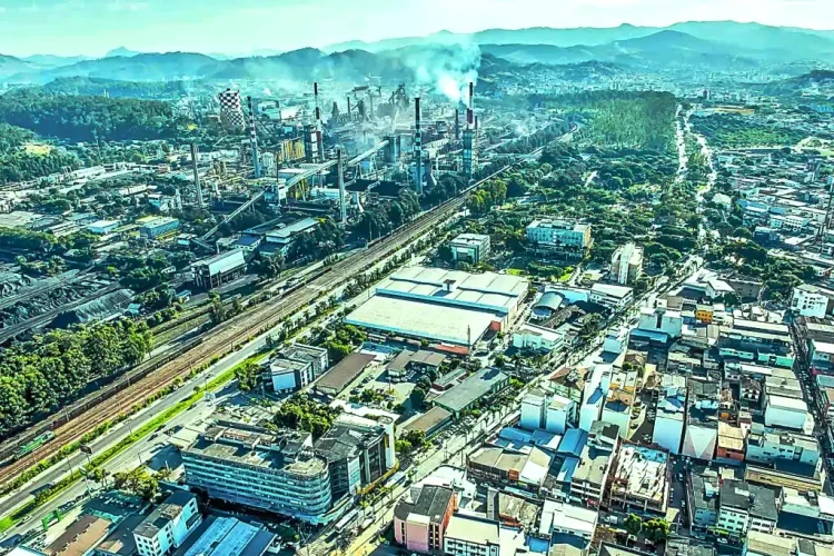 Vista aérea do Vale do Aço, em Minas Gerais, mostrando área urbana, vias, linha férrea e complexo industrial ao fundo.
