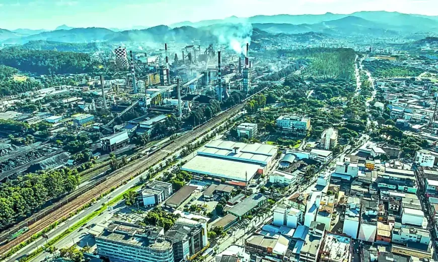 Vista aérea do Vale do Aço, em Minas Gerais, mostrando área urbana, vias, linha férrea e complexo industrial ao fundo.